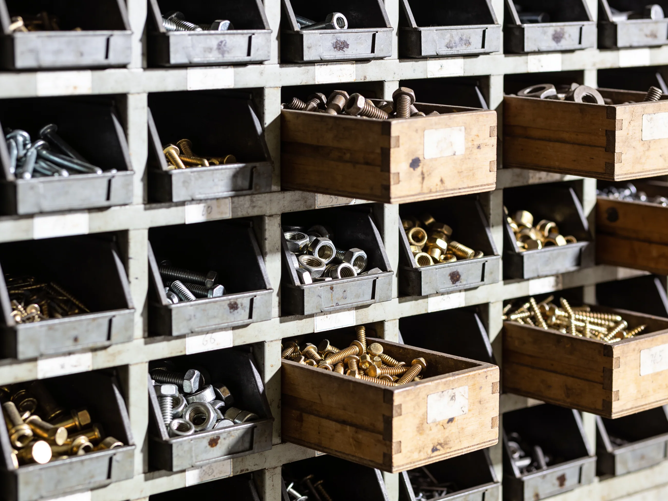 A wall of open steel parts bins in a working hardware shop, each holding a different fastener or fitting.